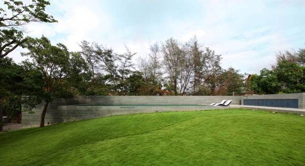 Spasm Architects clad Indian house in local stone and wrap it around a sunken courtyard.