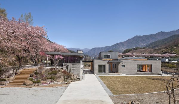 Rooftop bridge connects riverside house and roadside cafe in a South Korean valley