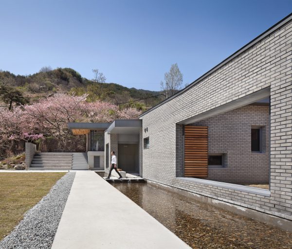 Rooftop bridge connects riverside house and roadside cafe in a South Korean valley