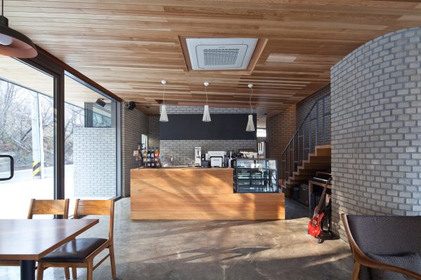 Rooftop bridge connects riverside house and roadside cafe in a South Korean valley