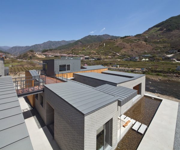 Rooftop bridge connects riverside house and roadside cafe in a South Korean valley