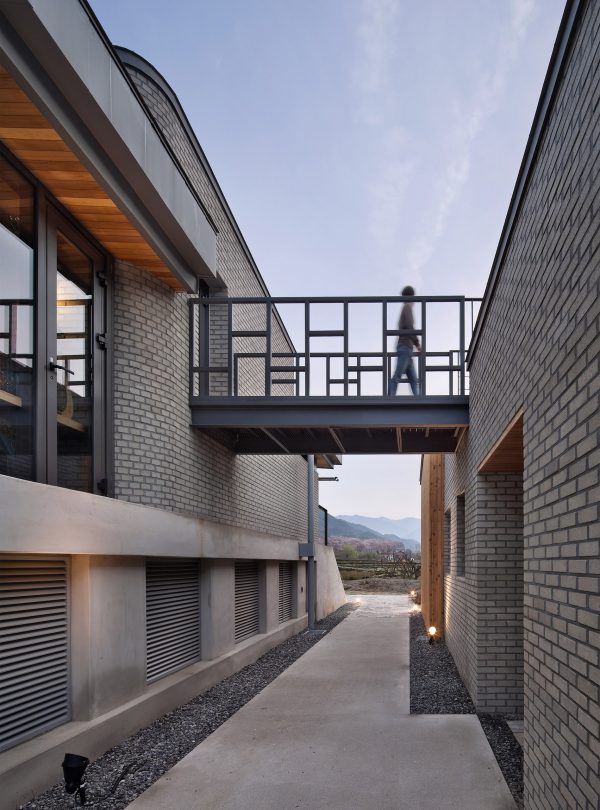Rooftop bridge connects riverside house and roadside cafe in a South Korean valley