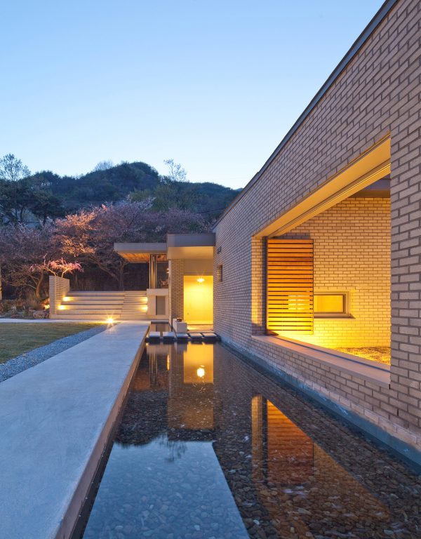 Rooftop bridge connects riverside house and roadside cafe in a South Korean valley