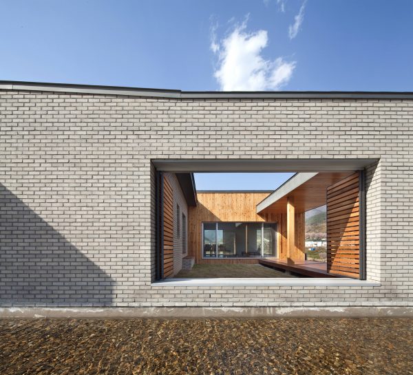 Rooftop bridge connects riverside house and roadside cafe in a South Korean valley