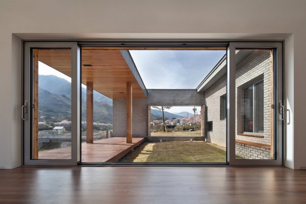 Rooftop bridge connects riverside house and roadside cafe in a South Korean valley