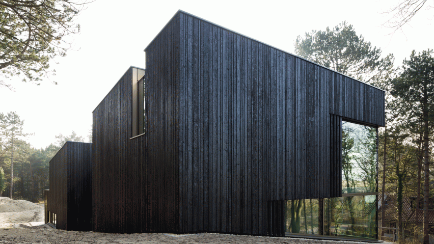 Charred timber and glass villa by VVKH Architecten is embedded in a sand dune
