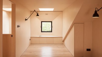 A plywood-lined bedroom in the loft of a London home