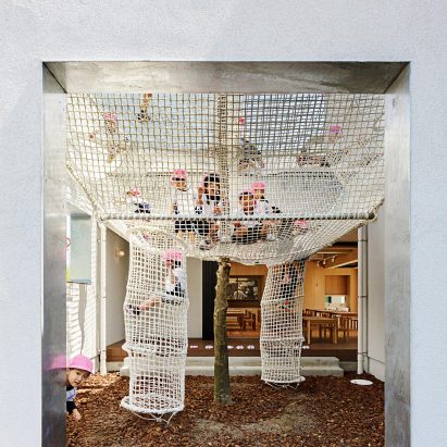 Climbing nets surround tree extending through balcony of Osaka nursery school