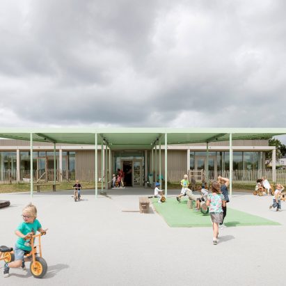 NL Architects completes Belgian school featuring low-lying rooms surrounded by a colonnade.