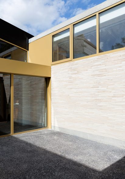 LT2A's brick school extension features porthole-like screens and gold-hued surfaces