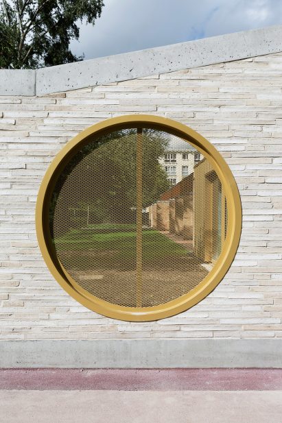 LT2A's brick school extension features porthole-like screens and gold-hued surfaces