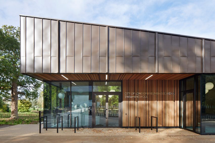 British firm Hawkins\Brown has completed a swimming-pool building at a school in Surrey, England, featuring an exposed timber frame that incorporates windows looking out onto the surrounding woodland.