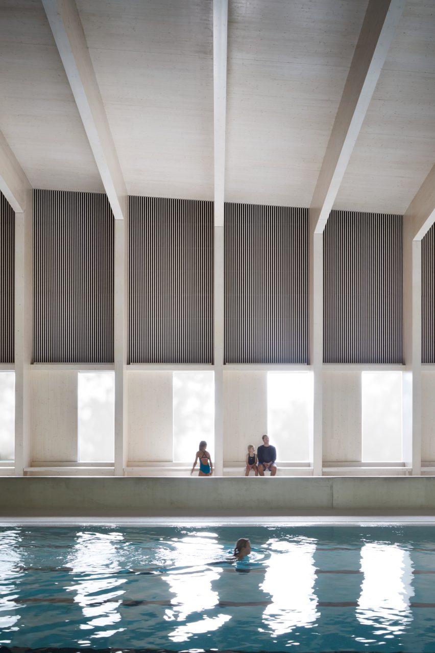 British firm Hawkins\Brown has completed a swimming-pool building at a school in Surrey, England, featuring an exposed timber frame that incorporates windows looking out onto the surrounding woodland.