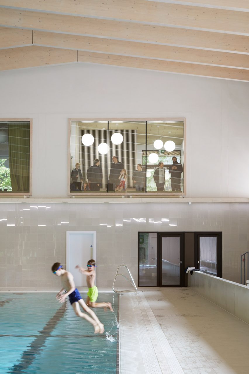 British firm Hawkins\Brown has completed a swimming-pool building at a school in Surrey, England, featuring an exposed timber frame that incorporates windows looking out onto the surrounding woodland.
