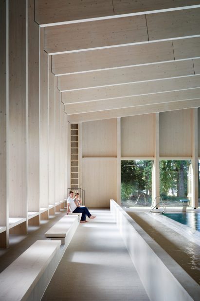 British firm Hawkins\Brown has completed a swimming-pool building at a school in Surrey, England, featuring an exposed timber frame that incorporates windows looking out onto the surrounding woodland.