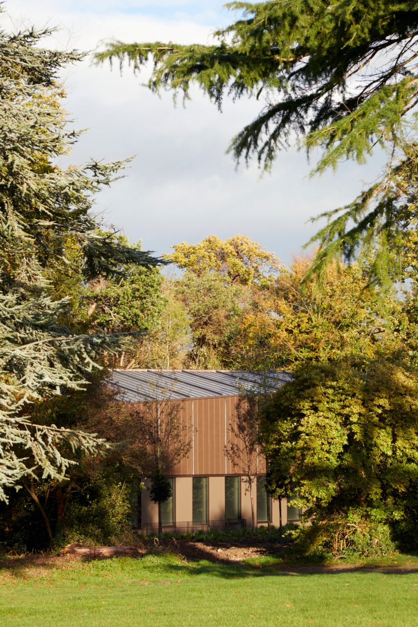 British firm Hawkins\Brown has completed a swimming-pool building at a school in Surrey, England, featuring an exposed timber frame that incorporates windows looking out onto the surrounding woodland.