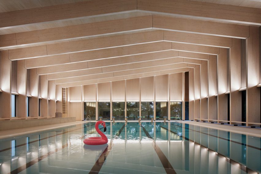 British firm Hawkins\Brown has completed a swimming-pool building at a school in Surrey, England, featuring an exposed timber frame that incorporates windows looking out onto the surrounding woodland.