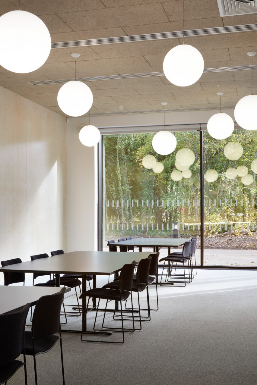 British firm Hawkins\Brown has completed a swimming-pool building at a school in Surrey, England, featuring an exposed timber frame that incorporates windows looking out onto the surrounding woodland.