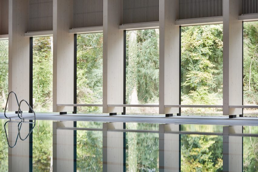British firm Hawkins\Brown has completed a swimming-pool building at a school in Surrey, England, featuring an exposed timber frame that incorporates windows looking out onto the surrounding woodland.