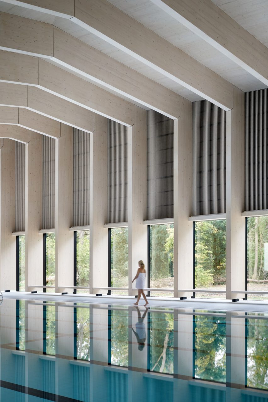 British firm Hawkins\Brown has completed a swimming-pool building at a school in Surrey, England, featuring an exposed timber frame that incorporates windows looking out onto the surrounding woodland.