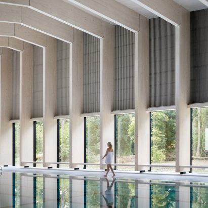 British firm Hawkins\Brown has completed a swimming-pool building at a school in Surrey, England, featuring an exposed timber frame that incorporates windows looking out onto the surrounding woodland.