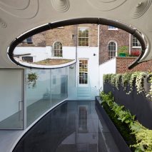Curved opening frames reflective pool in London house extension by Tonkin Liu