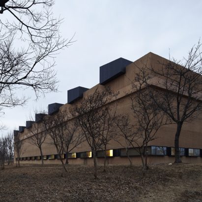 Steel-clad clerestory windows protrude from concrete badminton hall by JHW IROJE Architects