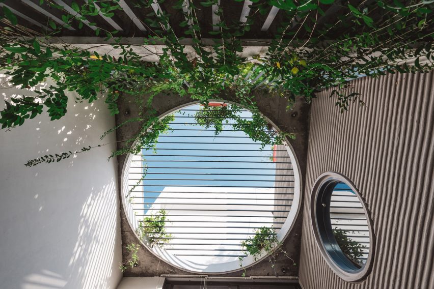 Living spaces at this house in the Indian city of Surat are arranged around a verdant courtyard lined with glass walls that can be retracted to open the interior up to the outdoors