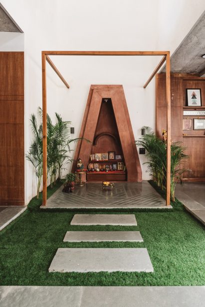 Living spaces at this house in the Indian city of Surat are arranged around a verdant courtyard lined with glass walls that can be retracted to open the interior up to the outdoors