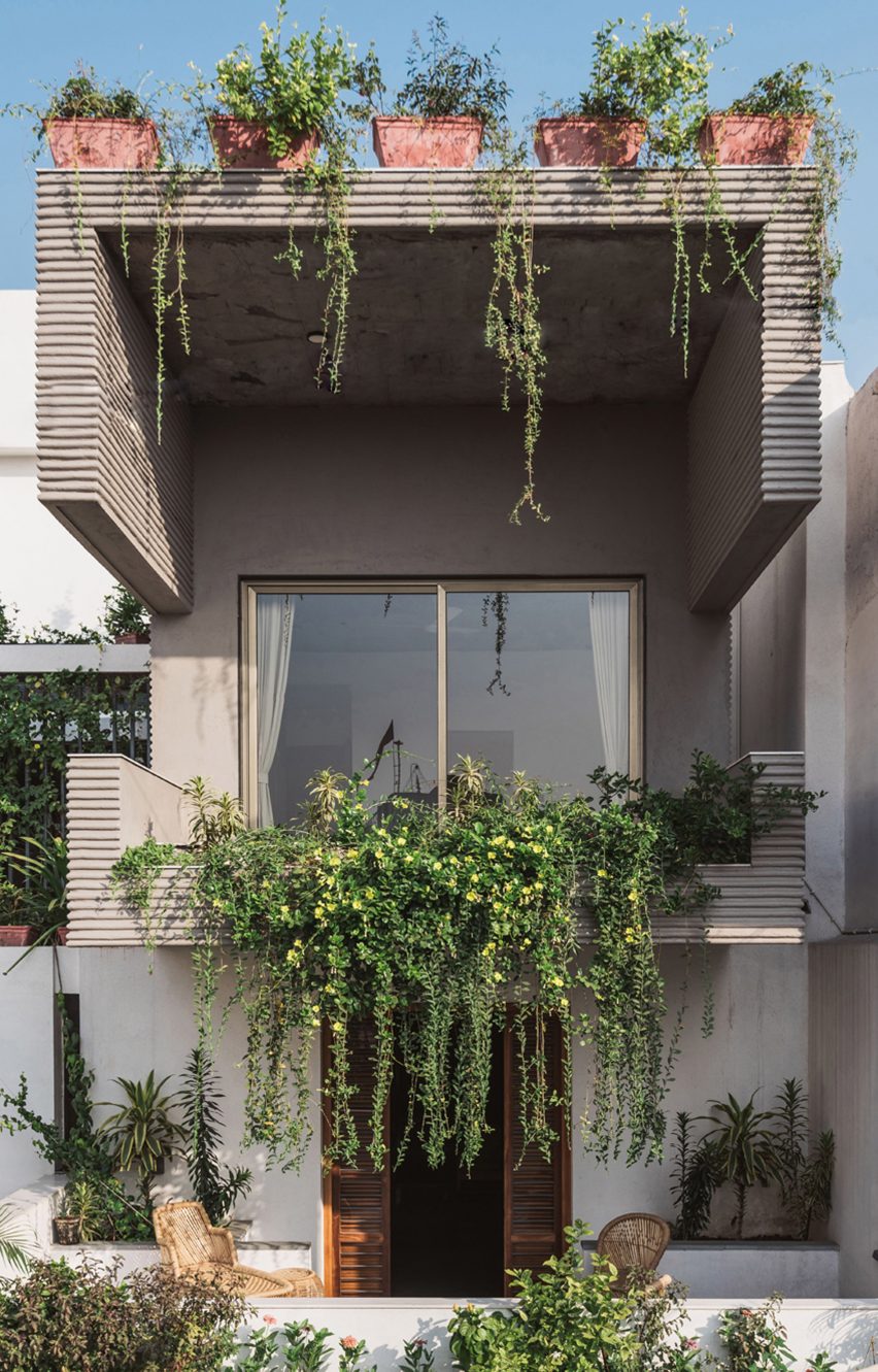 Living spaces at this house in the Indian city of Surat are arranged around a verdant courtyard lined with glass walls that can be retracted to open the interior up to the outdoors
