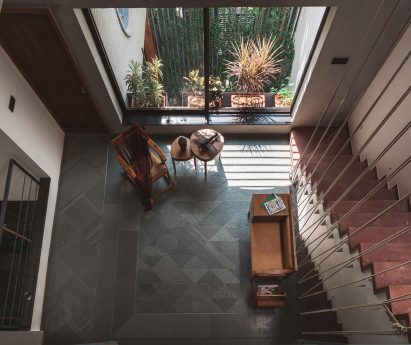 Living spaces at this house in the Indian city of Surat are arranged around a verdant courtyard lined with glass walls that can be retracted to open the interior up to the outdoors