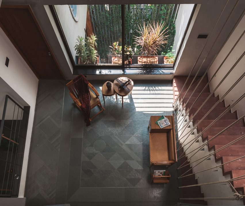 Living spaces at this house in the Indian city of Surat are arranged around a verdant courtyard lined with glass walls that can be retracted to open the interior up to the outdoors