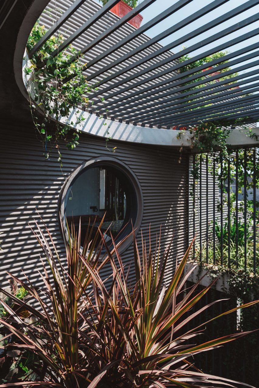 Living spaces at this house in the Indian city of Surat are arranged around a verdant courtyard lined with glass walls that can be retracted to open the interior up to the outdoors