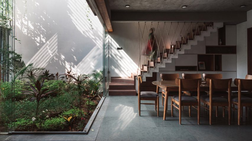Living spaces at this house in the Indian city of Surat are arranged around a verdant courtyard lined with glass walls that can be retracted to open the interior up to the outdoors.