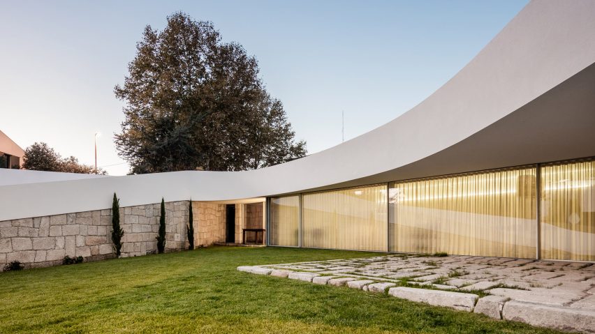 Curving roof and stone walls create seclusion for Portuguese house by NOARQ