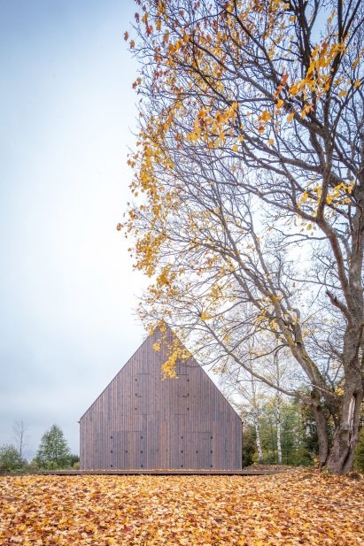 Aketuri Architektai conceals windows and doors behind large timber shutters at Lithuanian lakeside retreat