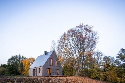 Aketuri Architektai conceals windows and doors behind large timber shutters at Lithuanian lakeside retreat