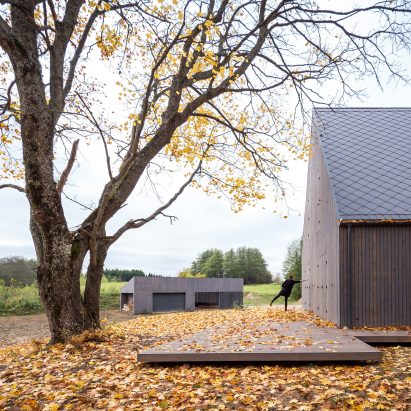 Aketuri Architektai conceals windows and doors behind large timber shutters at Lithuanian lakeside retreat