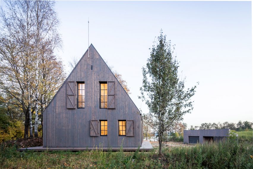Aketuri Architektai conceals windows and doors behind large timber shutters at Lithuanian lakeside retreat
