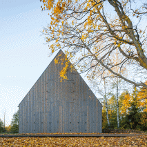 Aketuri Architektai conceals windows and doors behind large timber shutters at Lithuanian lakeside retreat