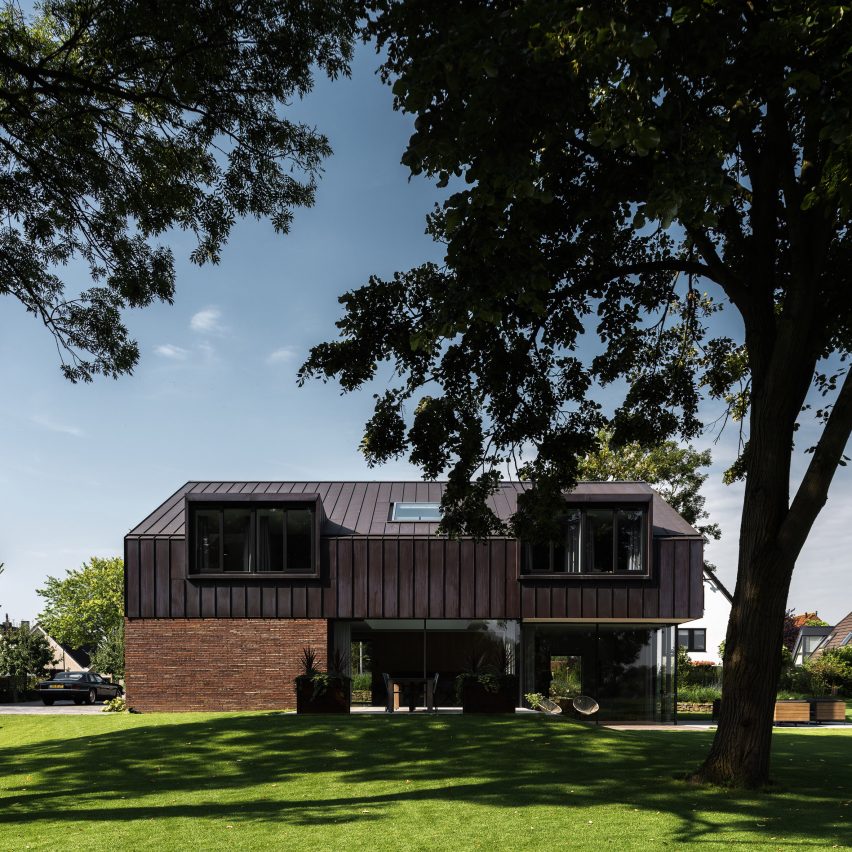 Villa IJsselzig by EVA Architecten is a riverside home featuring red-brick walls and a patinated copper roof