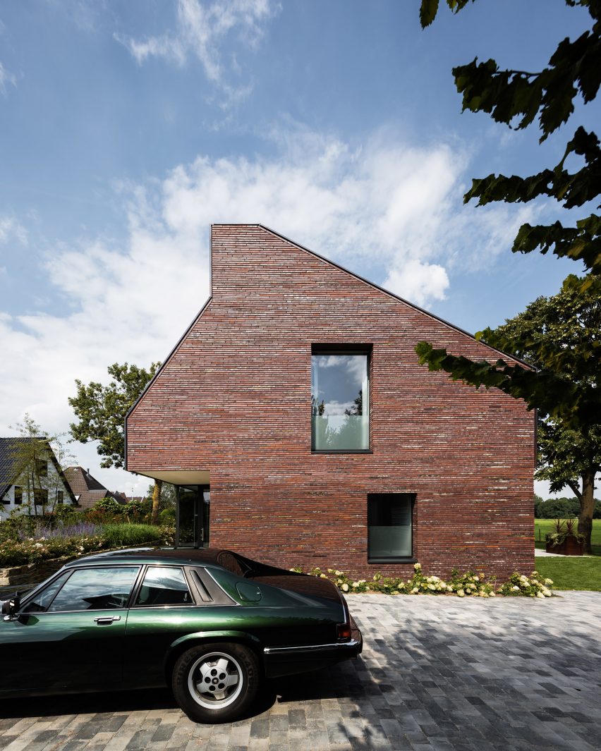 Villa IJsselzig by EVA Architecten is a riverside home featuring red-brick walls and a patinated copper roof