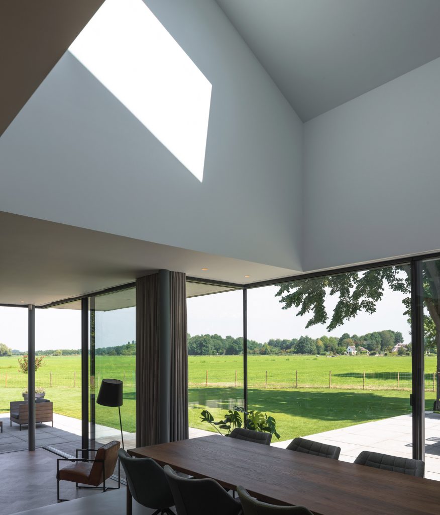 Villa IJsselzig by EVA Architecten is a riverside home featuring red-brick walls and a patinated copper roof