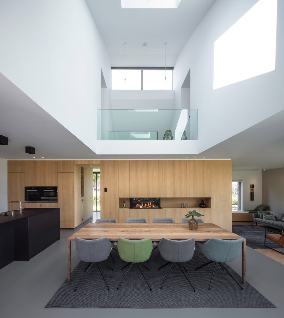 Villa IJsselzig by EVA Architecten is a riverside home featuring red-brick walls and a patinated copper roof