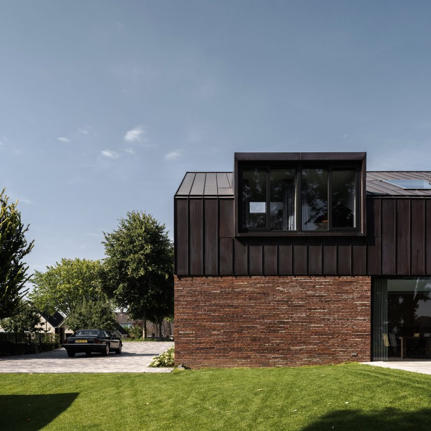 Villa IJsselzig by EVA Architecten is a riverside home featuring red-brick walls and a patinated copper roof