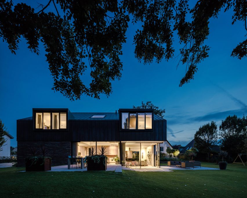 Villa IJsselzig by EVA Architecten is a riverside home featuring red-brick walls and a patinated copper roof
