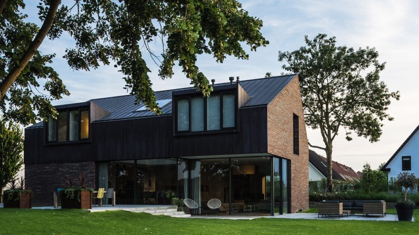 Villa IJsselzig by EVA Architecten is a riverside home featuring red-brick walls and a patinated copper roof