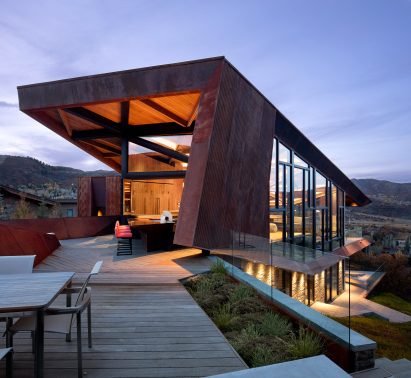 Photograph showing angular building split over multiple levels with terrace and overhanging roofline