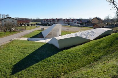 Sloping concrete volumes enclose social hub and chapel in a Slovenian village