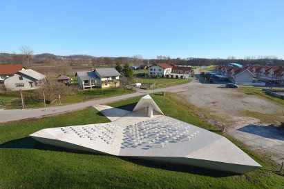 Sloping concrete volumes enclose social hub and chapel in a Slovenian village
